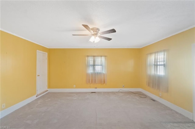 carpeted spare room with ceiling fan, ornamental molding, and a healthy amount of sunlight