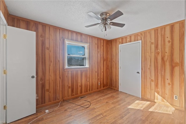 unfurnished room featuring a textured ceiling, ceiling fan, and light hardwood / wood-style flooring