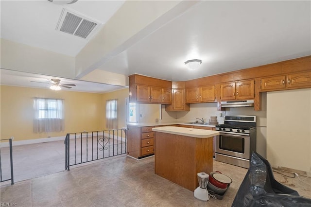 kitchen featuring ceiling fan, sink, gas stove, and a center island