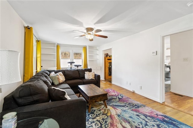 living room with wood-type flooring, ceiling fan, and built in shelves