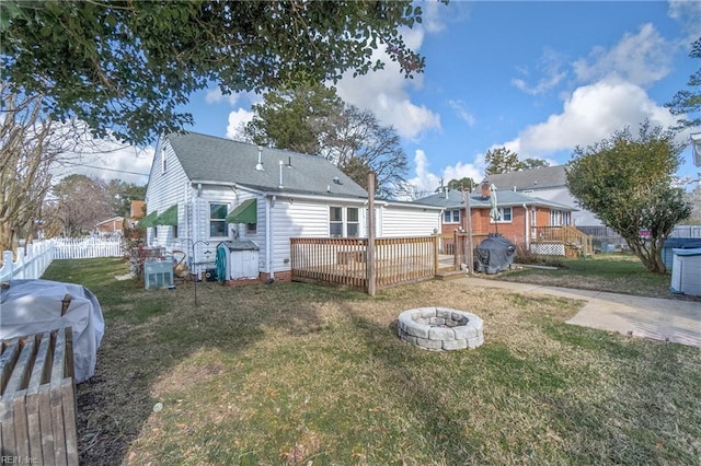 back of house with an outdoor fire pit, a deck, and a yard