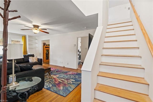 living room featuring built in shelves, ceiling fan, and hardwood / wood-style floors