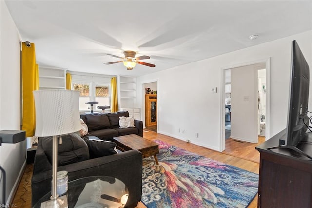 living room with built in features, ceiling fan, and hardwood / wood-style floors