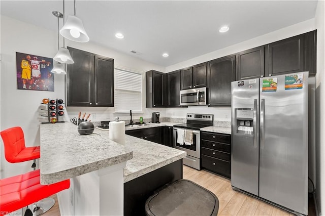 kitchen with stainless steel appliances, a breakfast bar area, hanging light fixtures, and kitchen peninsula