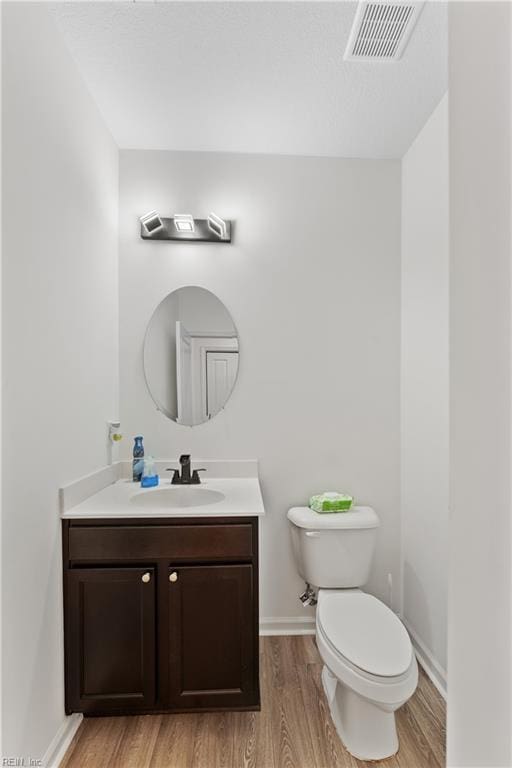 bathroom featuring toilet, vanity, and hardwood / wood-style floors