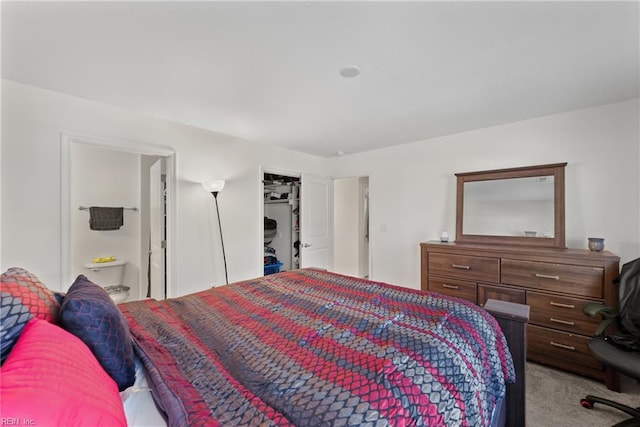 bedroom with ensuite bathroom, a closet, and light carpet