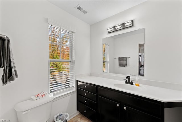 bathroom featuring a healthy amount of sunlight, vanity, and toilet