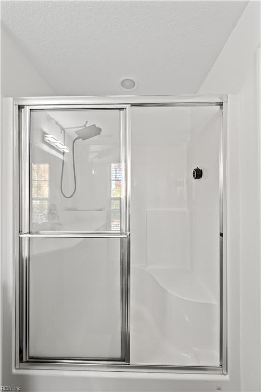 bathroom with a textured ceiling and an enclosed shower