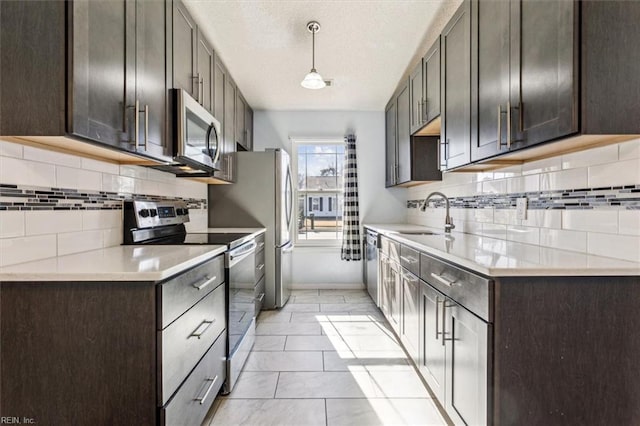 kitchen featuring stainless steel appliances, sink, backsplash, hanging light fixtures, and dark brown cabinetry