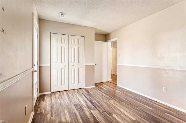 unfurnished bedroom with a textured ceiling, hardwood / wood-style floors, and a closet