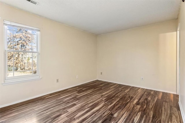 empty room with dark hardwood / wood-style flooring and a wealth of natural light