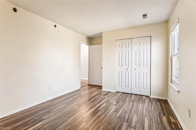 unfurnished bedroom with dark hardwood / wood-style flooring, a closet, and a textured ceiling