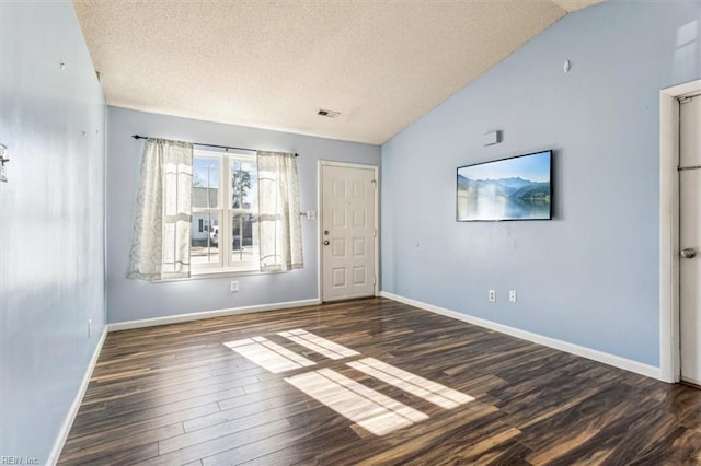 spare room featuring lofted ceiling, a textured ceiling, and dark hardwood / wood-style floors