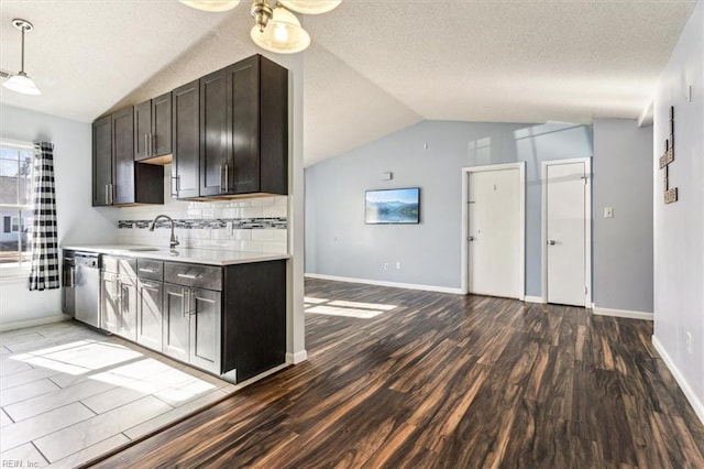 kitchen with decorative light fixtures, lofted ceiling, tasteful backsplash, stainless steel dishwasher, and dark wood-type flooring