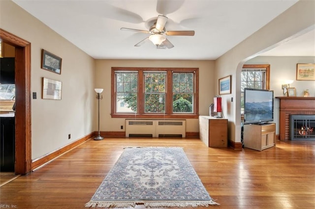 sitting room with ceiling fan, light hardwood / wood-style flooring, a fireplace, and radiator