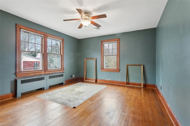 interior space with wood-type flooring, radiator heating unit, and ceiling fan