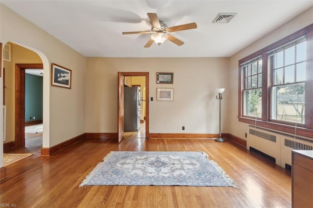 interior space with ceiling fan, radiator heating unit, and hardwood / wood-style flooring