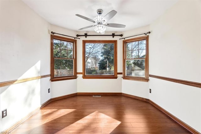 empty room featuring ceiling fan, a healthy amount of sunlight, and hardwood / wood-style flooring