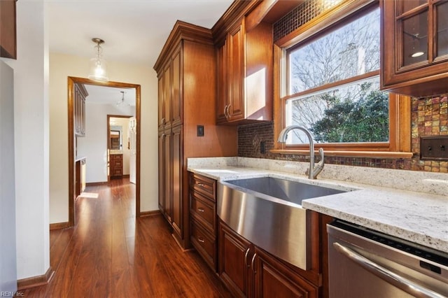 kitchen featuring plenty of natural light, dishwasher, light stone counters, and decorative light fixtures