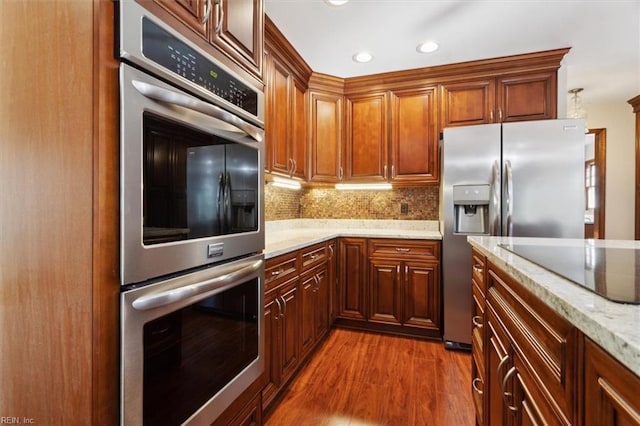 kitchen with stainless steel appliances, dark hardwood / wood-style flooring, light stone counters, and tasteful backsplash