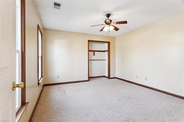 unfurnished bedroom with ceiling fan, light carpet, and multiple windows