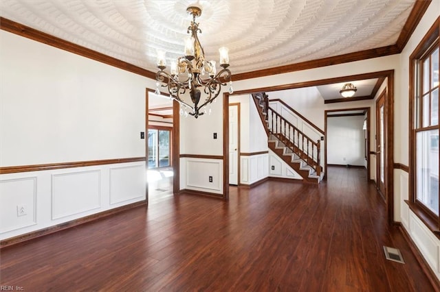 spare room with dark wood-type flooring, crown molding, and a notable chandelier