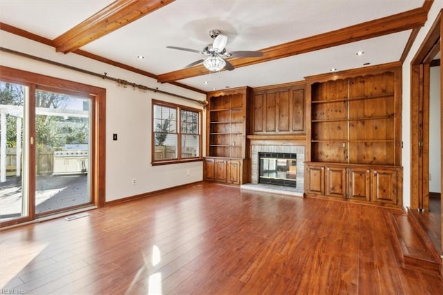 unfurnished living room featuring ceiling fan, a fireplace, crown molding, hardwood / wood-style flooring, and built in features