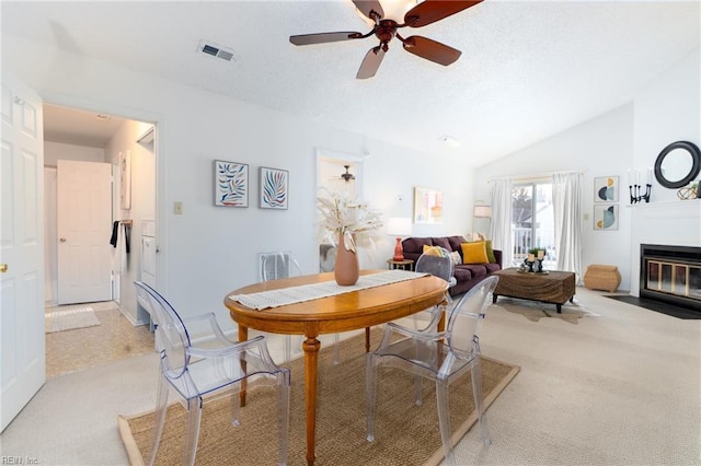 carpeted dining area featuring ceiling fan and vaulted ceiling