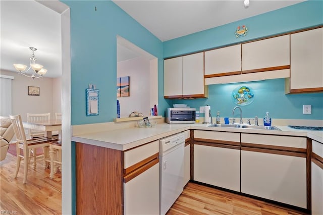 kitchen featuring decorative light fixtures, sink, white dishwasher, white cabinetry, and light hardwood / wood-style flooring