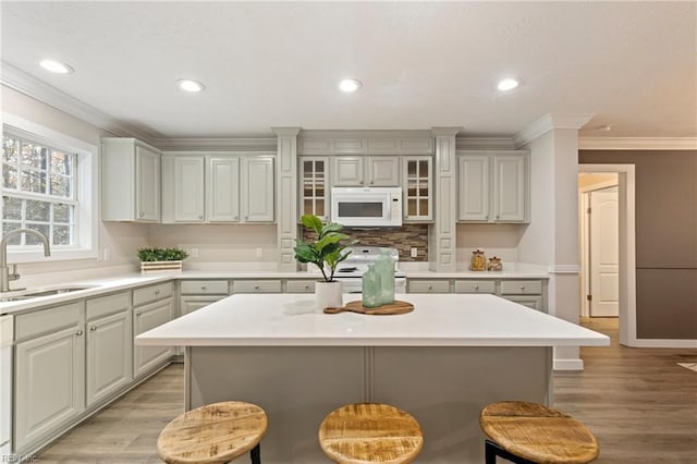 kitchen with white appliances, a breakfast bar, a center island, and sink