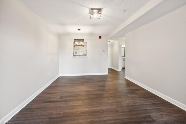 spare room featuring dark hardwood / wood-style floors and a textured ceiling