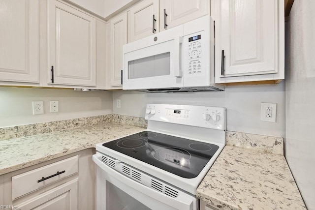 kitchen featuring white cabinets, light stone counters, and white appliances