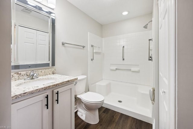 bathroom featuring toilet, vanity, a shower, and hardwood / wood-style flooring