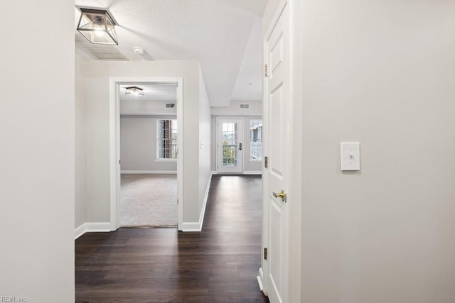 hall featuring a textured ceiling and dark hardwood / wood-style floors