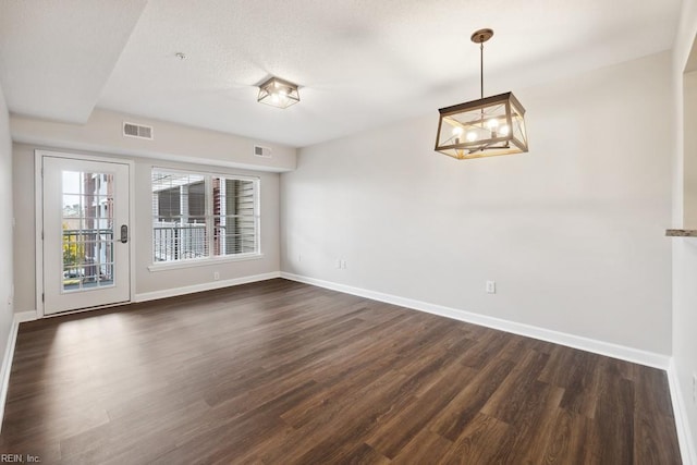 unfurnished dining area with dark hardwood / wood-style floors and an inviting chandelier