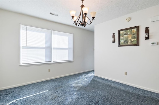 carpeted spare room featuring an inviting chandelier and a textured ceiling