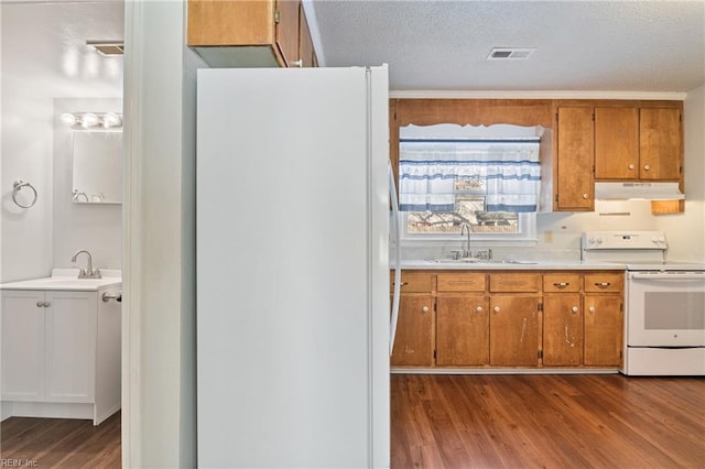 kitchen with light wood-type flooring, a textured ceiling, sink, and white appliances