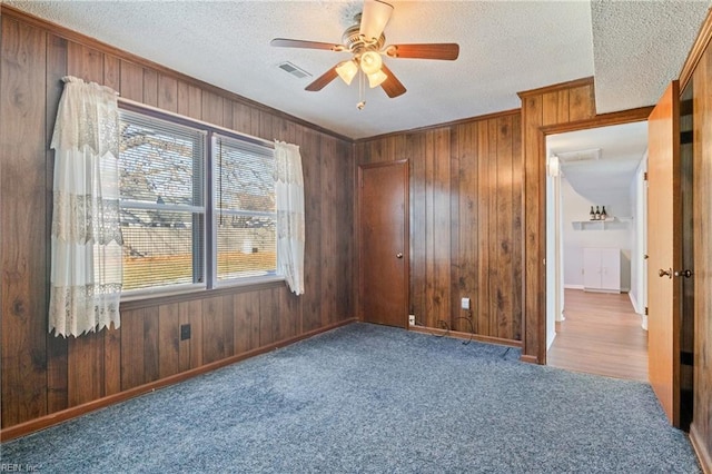 empty room with ceiling fan, crown molding, carpet floors, and a textured ceiling