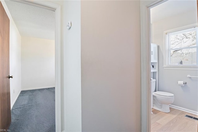 bathroom featuring toilet, wood-type flooring, and a textured ceiling