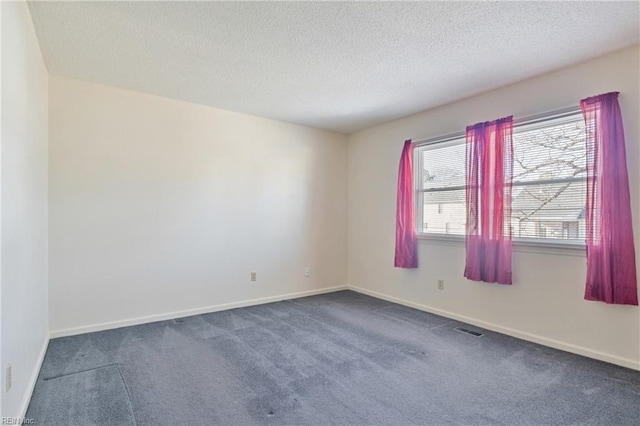 spare room with dark carpet, a wealth of natural light, and a textured ceiling