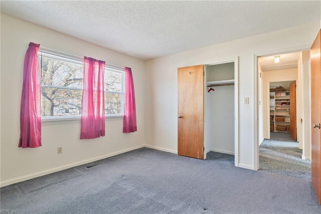 unfurnished bedroom with a textured ceiling and dark carpet