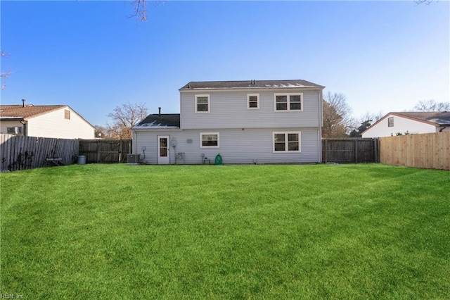 rear view of house featuring central air condition unit and a lawn