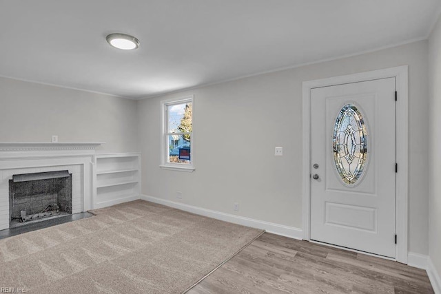 foyer entrance featuring a brick fireplace and light hardwood / wood-style flooring