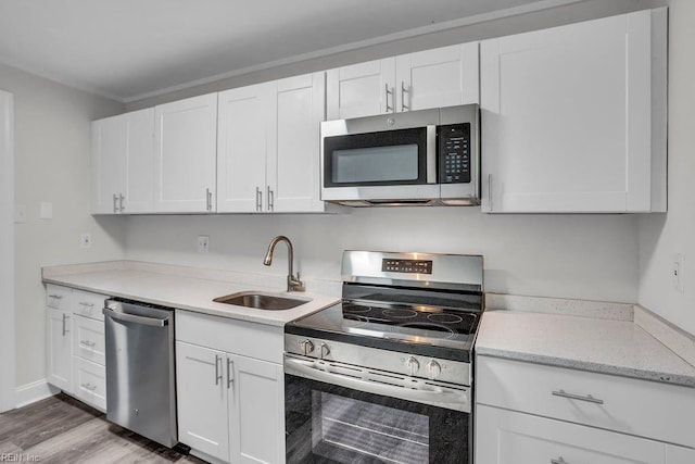 kitchen with hardwood / wood-style flooring, sink, white cabinets, and stainless steel appliances