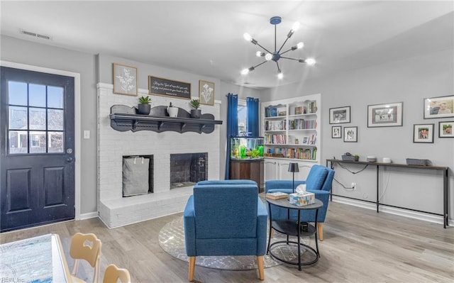 living area with light hardwood / wood-style floors, a chandelier, and a fireplace