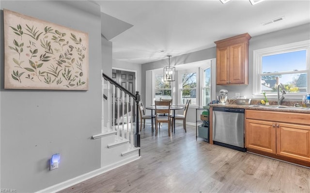 kitchen with sink, hanging light fixtures, a chandelier, light wood-type flooring, and stainless steel dishwasher