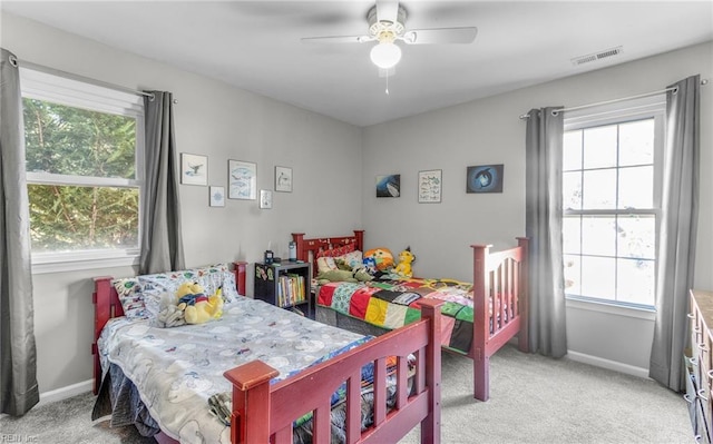 carpeted bedroom featuring ceiling fan and multiple windows