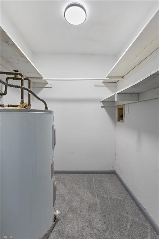 walk in closet featuring electric water heater and carpet floors