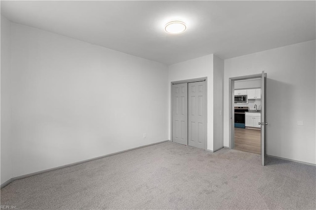 unfurnished bedroom with a closet, light colored carpet, and sink