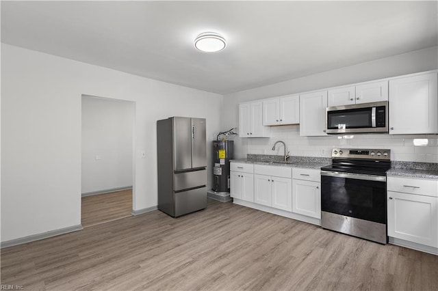 kitchen featuring white cabinets, appliances with stainless steel finishes, decorative backsplash, light hardwood / wood-style floors, and electric water heater